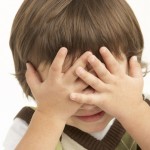 Studio Portrait Of Young Boy Covering Eyes